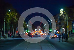 View of the street in the city at night blurred, where riding cars, trams glow lights and vehicle headlights.