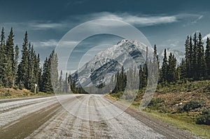 View of street highway with mountains and trees with blue sky and clouds. Banff National Park Canada Rocky Mountains.