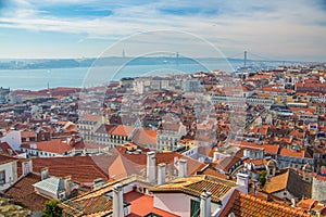 View of the streets and the orange roofs of the old town. Lisbon, Portugal. In the distance, see the bridge of April 25