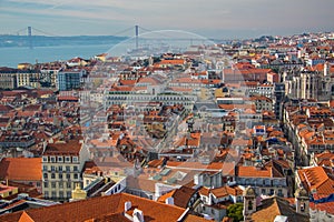 View of the streets and the orange roofs of the old town. Lisbon, Portugal. In the distance, see the bridge of April 25