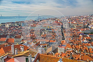 View of the streets and the orange roofs of the old town. Lisbon, Portugal. In the distance, see the bridge of April 25