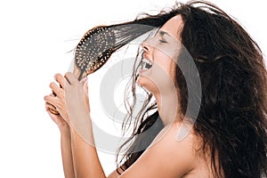 View of stressed brunette woman with wavy unruly in comb crying isolated on white