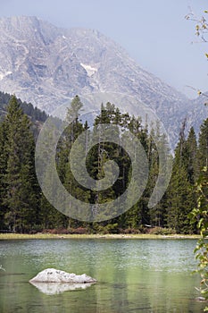 A view of String Lake in Grand Teton National Park with a white rock and mountains in the back.