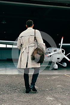 View of stylish businessman in coat standing near plane