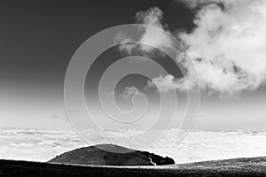 View of Subasio mountain Umbria over valley filled by fog, beneath a wide sky with white clouds