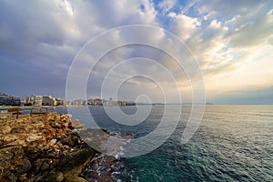 View of the summer city by the sea on a golden sunset with stunning clouds.