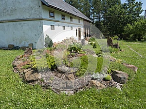 View on summer garden with beautiful rock garden with various alpine, rock plants, decorative grass and conifers and
