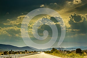 View of sun and rain clouds on rural road