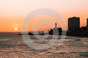 View of the sunset on the beach bar with the Barra Lighthouse in the background photo