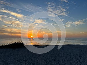 A view of a Sunset on the beach at Siesta Key, Florida with a blue cloudy sky