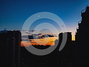 The view on the sunset and the moon in the suburb, urbanistic landscape.