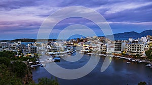 View of sunset over Lake Voulismeni at Agios Nikolaos, island of Crete, Greece - timelapse, zoom out, tilt