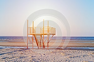 View of sunset sandy beach with red empty modern lifeguard tower