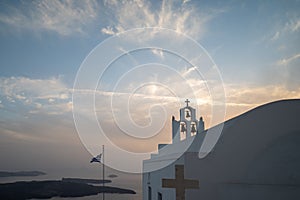 View of the sunset in Santorini with a Christian Greek Orthodox church with a bell tower