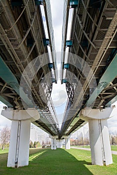 View of the supports and metal spans of the light metro on a clear sunny day against the blue sky. Transport railway