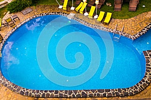 View of swimingpool with yellow chairs in background