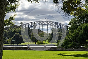 View of Sydney Harbour Bridge from botanical gardens, with people walking along foreshore