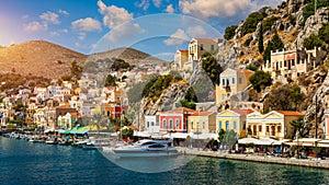 View on Symi (Simi) island harbor port, classical ship yachts, houses on island hills, Aegean Sea bay.