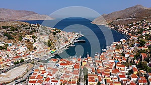View on Symi (Simi) island harbor port, classical ship yachts, houses on island hills, Aegean Sea bay.