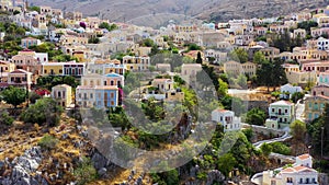 View on Symi Simi island harbor port, classical ship yachts, houses on island hills, Aegean Sea bay. Greece islands holidays