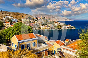 View on Symi Simi island harbor port, classical ship yachts, houses on island hills, Aegean Sea bay. Greece islands holidays