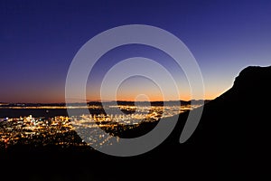 View of Table Mountain and Cape Town city at sunrise, With a king protea in foreground