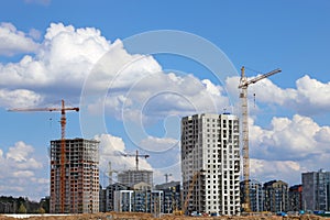 View of tall cranes and houses under construction