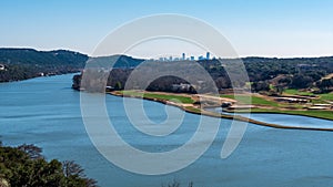 View from a tall hill of a river near Lake Travis with view of Austin skyline visible far away photo