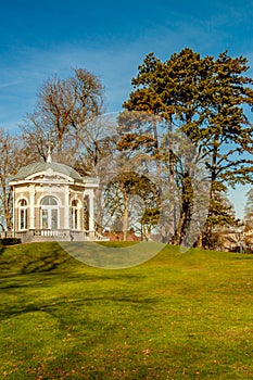 View of the Tea dome or Gloriette with neoclassical decorations on a hill with green grass and trees