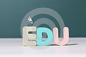 View of teacher figurine standing on EDU letters