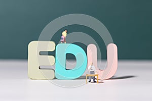 View of teacher and student figurines standing around EDU letters