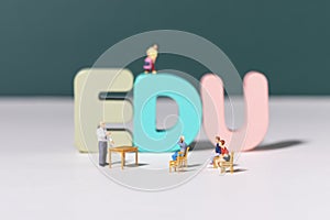 View of teacher and student figurines standing around EDU letters