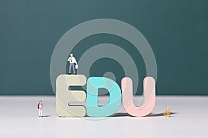 View of teacher and student figurines standing around EDU letters