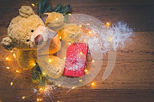 View of a teddy with a red wrapped present, and Christmas decorations on wooden background