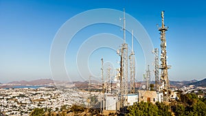 View of Telecommunication mast TV antennas at sunrise on mountain with city background. Antenna Telephone Communication