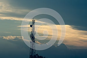 A view of telecommunication tower with a blue sky covered with clouds