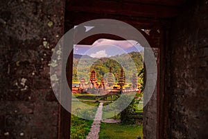 View through a temple doorway at sunset towards Pura Ulun Danu Tamblingan temple in the Buleleng Regency area of Bali, Indonesia,