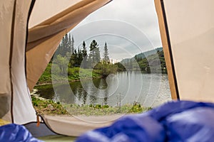View from tent on a mountain lake. Trips and expeditions in the wild. Concept of camping