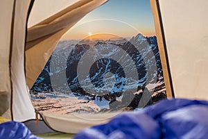 View from tent on snow-capped mountains. Trips and expeditions in the wild. Concept of camping