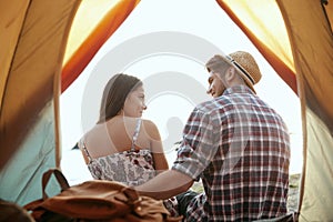 View from tent on young couple rest on beach