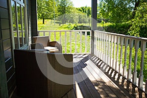 View from the terrace of a country wooden house to the garden through the white wooden railing of the terrace.