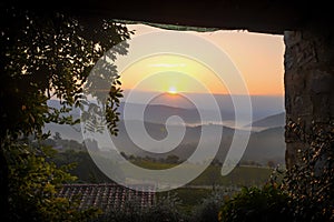 View from a terrace to a sunrise over foggy hills in the vineyards in Tuscany in Italy