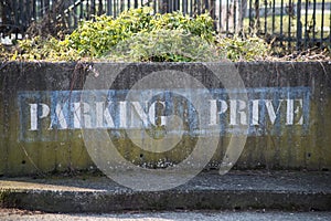 text on stoned wal in french :  parking prive, traduction in english, private parking photo