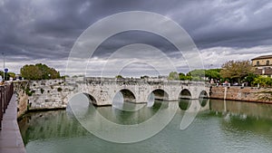 View of the Tiberius Bridge or Ponte di Augusto, a Roman bridge in Rimini, Italy, under a dramatic sky