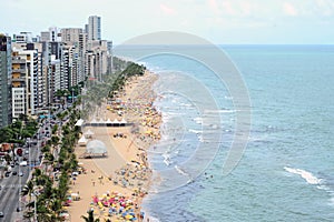 A view to the city beach with lots of Brazilian people sunbathing and swimming, a view from the top of a skyscraper.