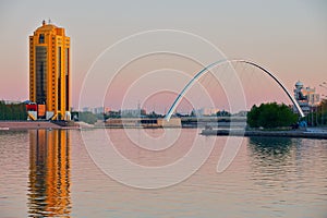 View to the city buildings and bridge over the Ishim river at dusk in Astana, Kazakhstan.