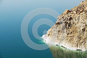 View to the cliff at the Dead sea shore with reflection in the water in Jordan.