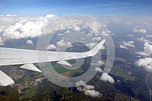 View to the earth from passenger supersonic airplane window flying high in the sky above white clouds