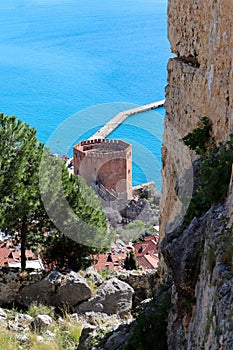 View to famous ancient landmark Red tower Kizil Kule in Turkey with Alanya bay and fortress wall