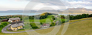 View to lake Attersee with green pasture meadows and Alps mountain range near Nussdorf Salzburg, Austria